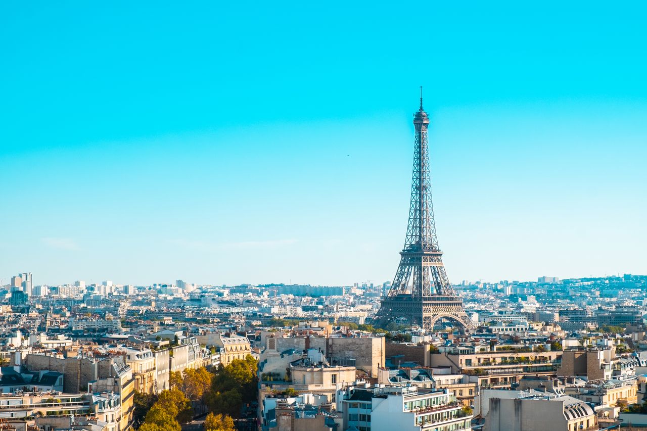 services-01 Eiffel Tower overlooking the cityscape of Paris under clear blue skies.