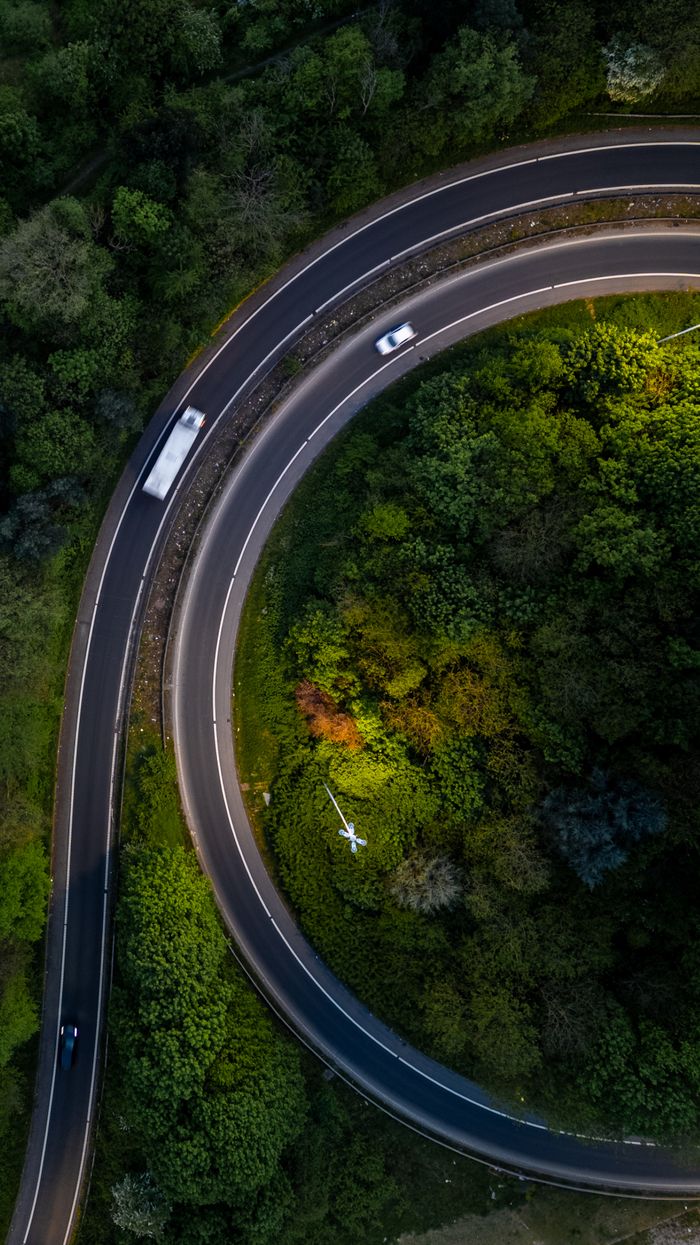 journey Stunning aerial view of a curved road surrounded by lush greenery in Leeds, United Kingdom.
